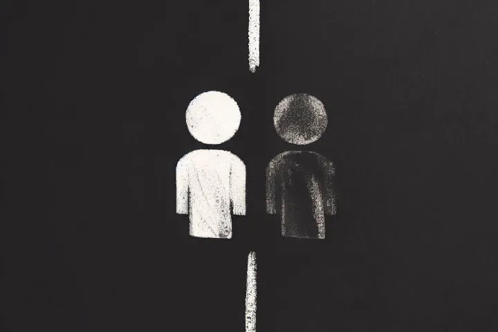 Duas pessoas desenhadas com giz, uma branca, uma negra, divididas por uma linha branca ao meio